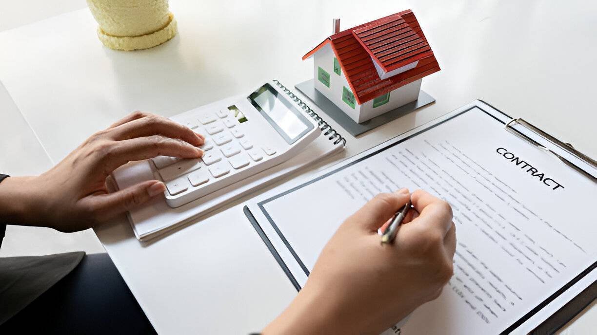 A woman signs a contract with a calculator and model house